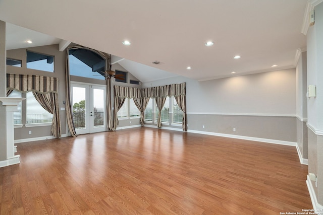 empty room featuring light wood finished floors, visible vents, baseboards, lofted ceiling, and french doors