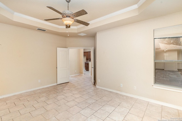 empty room featuring baseboards, visible vents, a ceiling fan, a raised ceiling, and crown molding