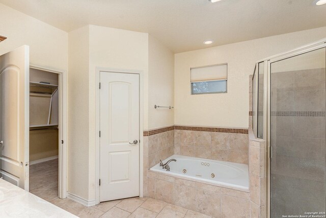 full bath featuring a stall shower, a walk in closet, a jetted tub, and tile patterned floors