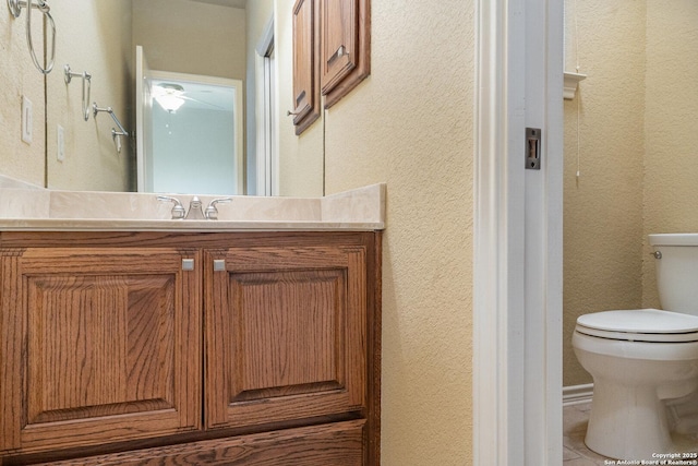 bathroom with toilet, a textured wall, and vanity