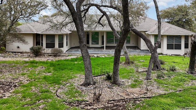 ranch-style house featuring a front yard, a patio area, and roof with shingles