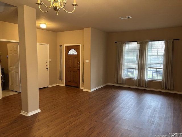 entrance foyer featuring dark wood-style floors, visible vents, a notable chandelier, and baseboards