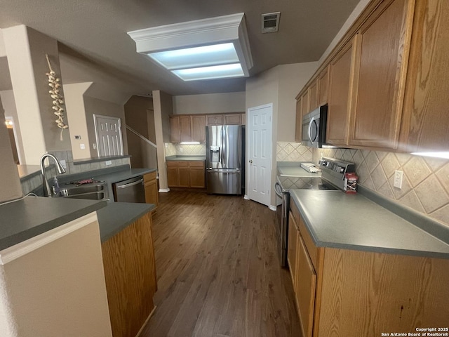 kitchen featuring visible vents, brown cabinetry, dark wood finished floors, dark countertops, and appliances with stainless steel finishes