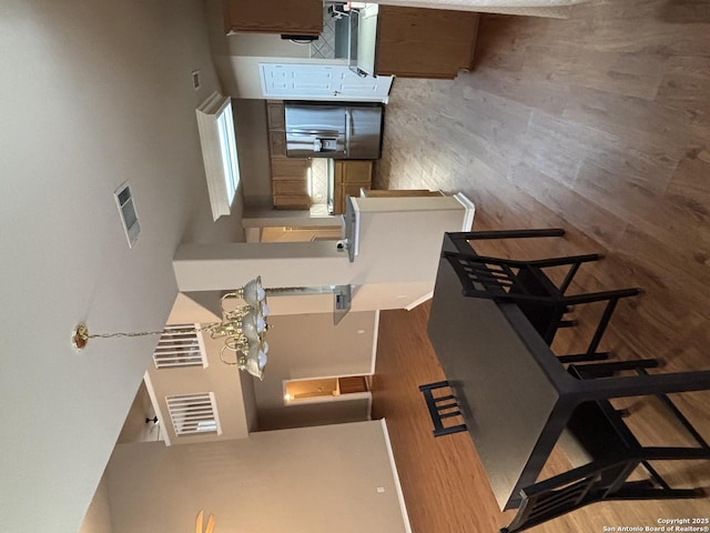 kitchen with dark wood-type flooring, a breakfast bar area, brown cabinetry, and light countertops