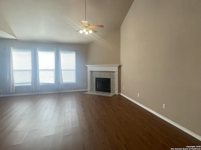 unfurnished living room with ceiling fan, light wood-type flooring, a tile fireplace, and baseboards