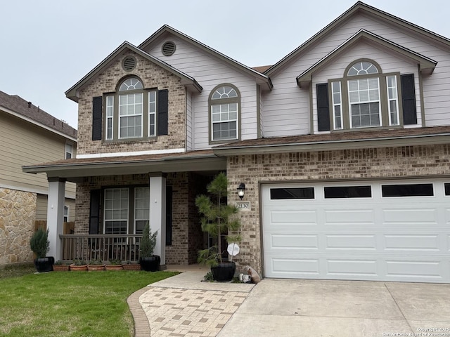 view of front of property featuring covered porch, concrete driveway, brick siding, and a front yard