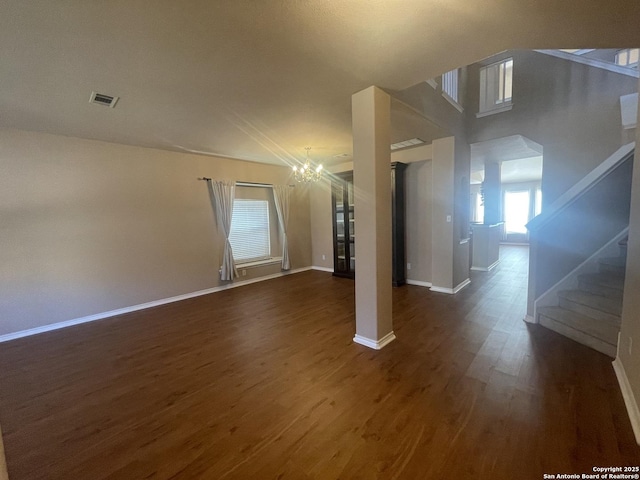 unfurnished living room with baseboards, visible vents, stairway, and dark wood-style flooring