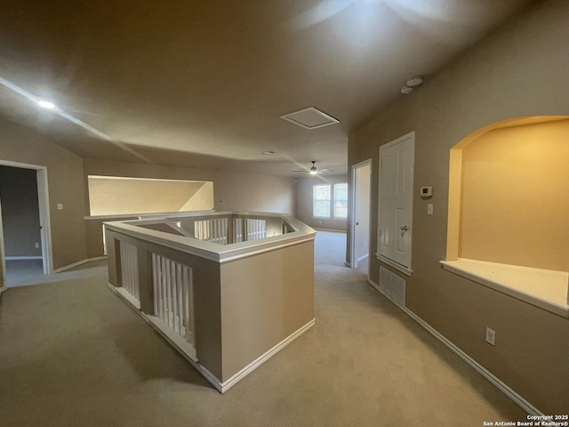 hall with baseboards, light carpet, visible vents, and an upstairs landing