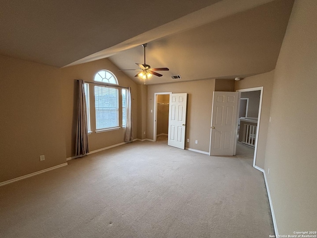 unfurnished bedroom with lofted ceiling, light carpet, visible vents, baseboards, and a walk in closet