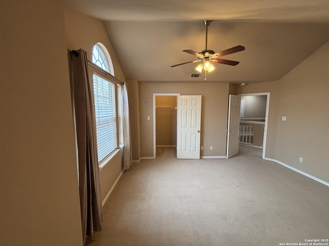 unfurnished bedroom featuring lofted ceiling, light colored carpet, visible vents, baseboards, and a spacious closet