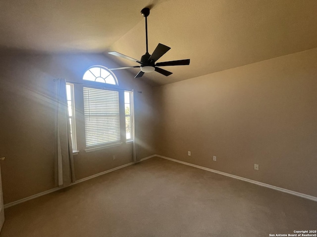 carpeted spare room featuring ceiling fan, lofted ceiling, and baseboards