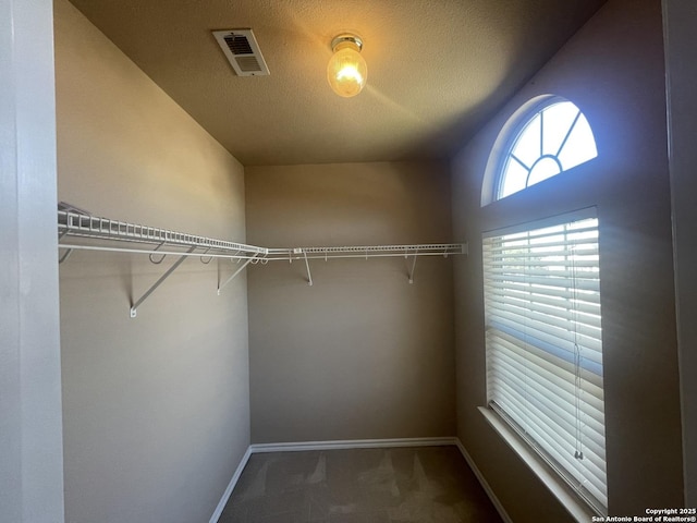 spacious closet with visible vents and dark carpet