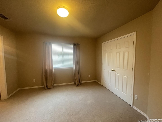 unfurnished bedroom featuring carpet floors, baseboards, and visible vents