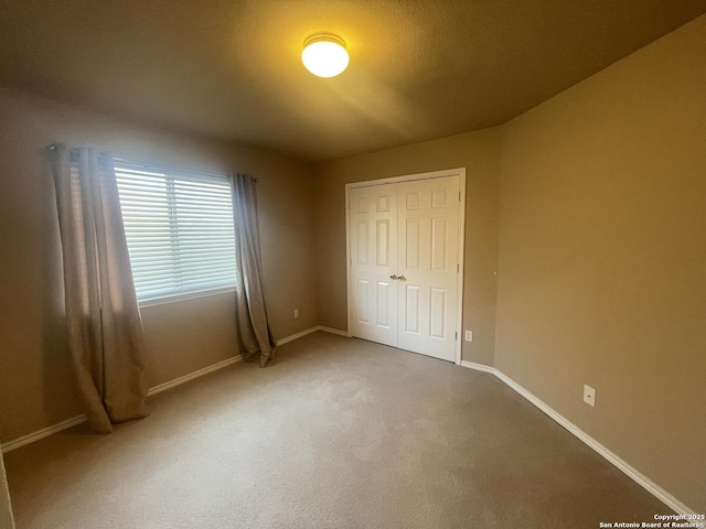 unfurnished bedroom featuring carpet, a closet, and baseboards