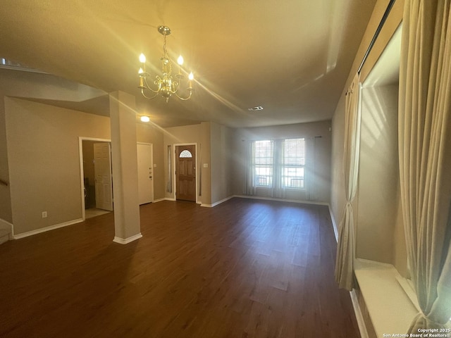 unfurnished living room featuring dark wood-style floors, a chandelier, and baseboards