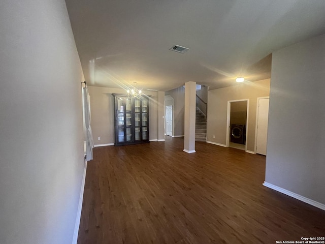 unfurnished living room featuring washer / dryer, baseboards, dark wood-style floors, and stairs