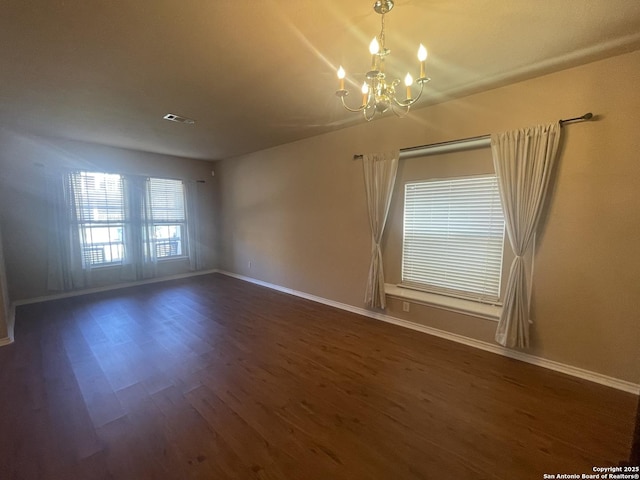 unfurnished room featuring a notable chandelier, baseboards, visible vents, and dark wood-type flooring