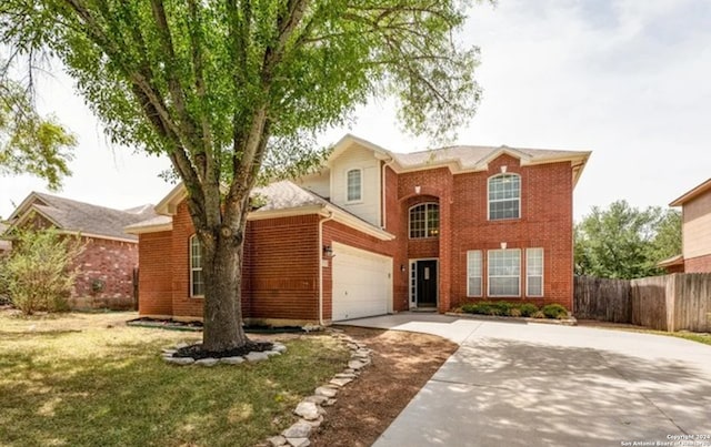 traditional-style house with driveway, fence, a front lawn, and brick siding