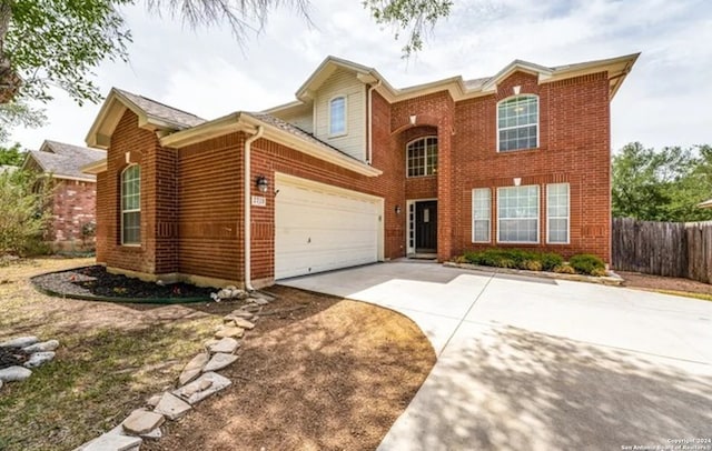 traditional-style house with a garage, concrete driveway, brick siding, and fence