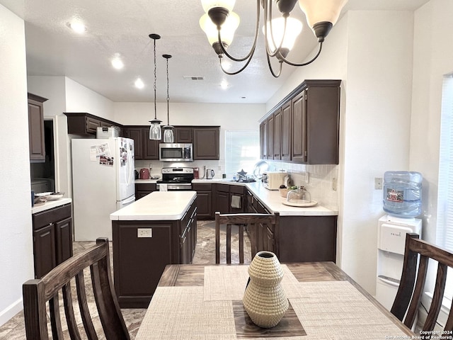 kitchen with a center island, light countertops, visible vents, appliances with stainless steel finishes, and dark brown cabinets