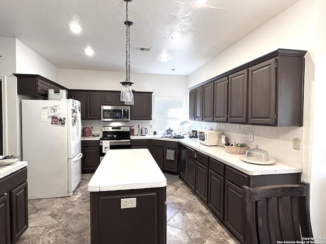 kitchen with stainless steel appliances, visible vents, light countertops, a center island, and pendant lighting