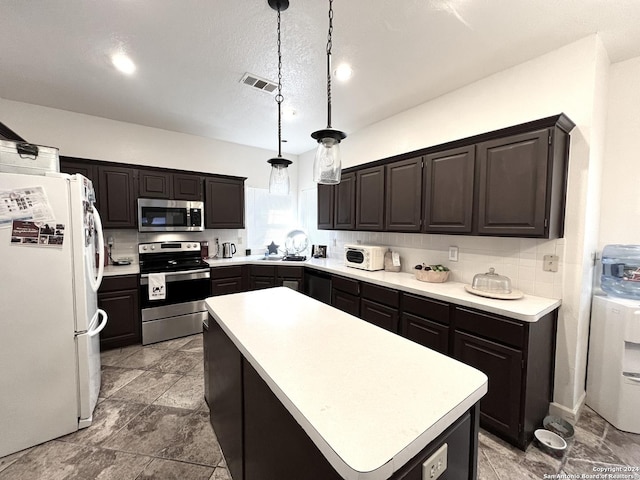 kitchen with decorative light fixtures, stainless steel appliances, light countertops, visible vents, and a kitchen island