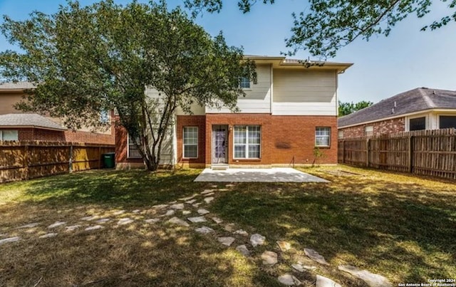 rear view of property with brick siding, a fenced backyard, a lawn, and a patio