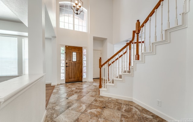 foyer entrance featuring a high ceiling, stairway, and baseboards