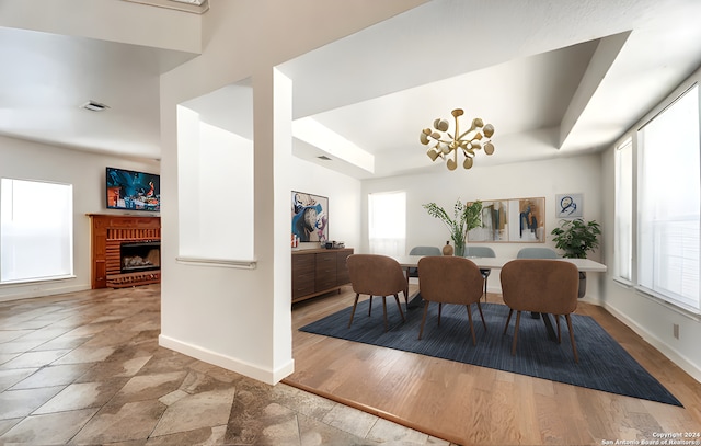 dining area with a raised ceiling, a notable chandelier, a fireplace, and baseboards