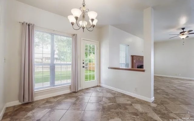 entryway with baseboards, a brick fireplace, ceiling fan with notable chandelier, and a healthy amount of sunlight