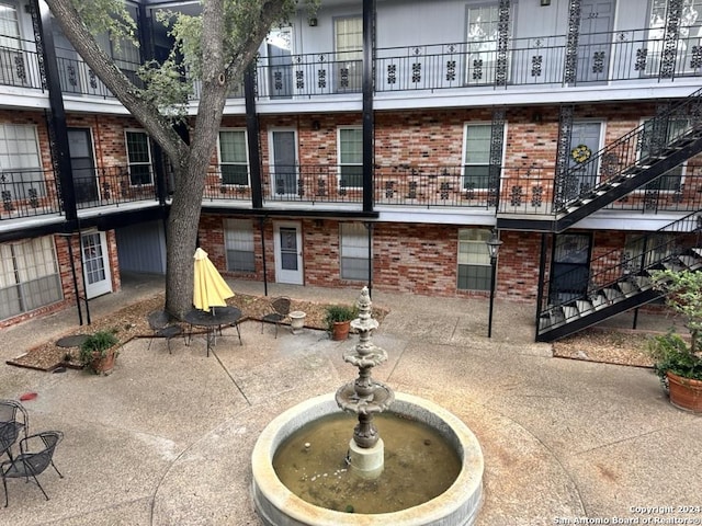 rear view of property featuring stairs, a patio, and brick siding