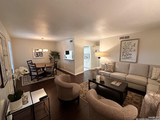 living area featuring baseboards, a textured ceiling, visible vents, and wood finished floors