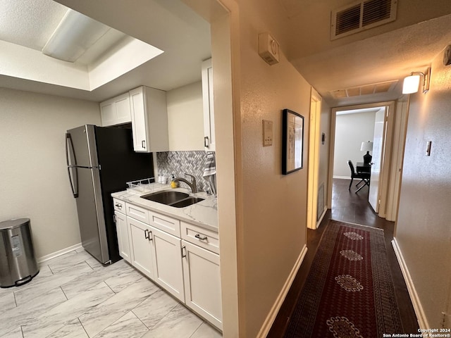 kitchen featuring marble finish floor, visible vents, white cabinets, and a sink