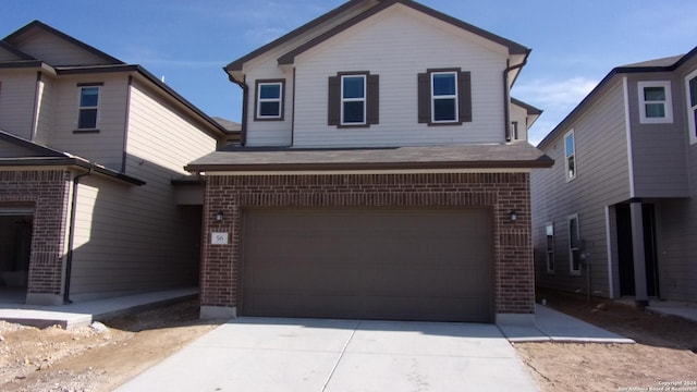 traditional-style home with a garage, driveway, and brick siding