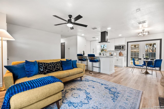 living area with french doors, a ceiling fan, visible vents, and light wood-style floors