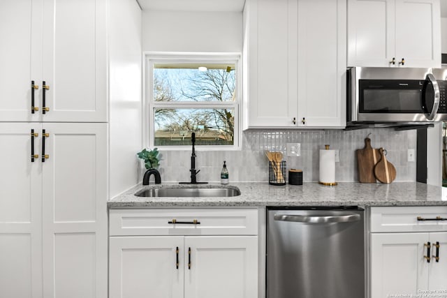 kitchen featuring tasteful backsplash, appliances with stainless steel finishes, a sink, and white cabinets