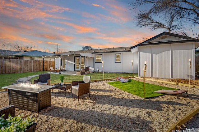 rear view of house with a yard, a patio, fence, and an outdoor living space with a fire pit