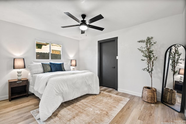 bedroom featuring ceiling fan, light wood-style flooring, and baseboards