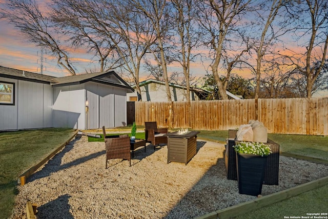 yard at dusk with a fire pit and fence