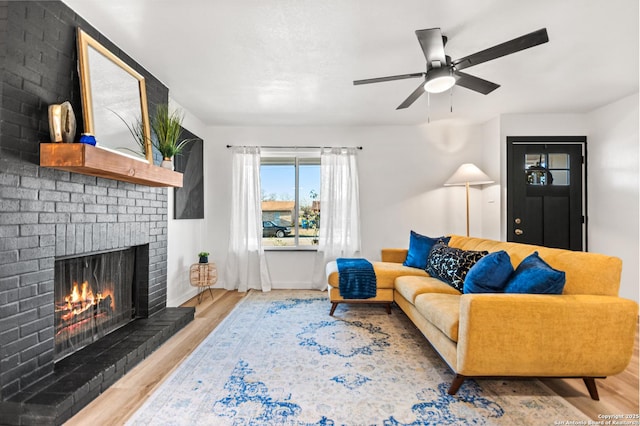 living room with ceiling fan, a fireplace, light wood-style flooring, and baseboards