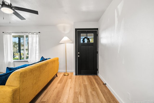 foyer with a ceiling fan, baseboards, and light wood finished floors