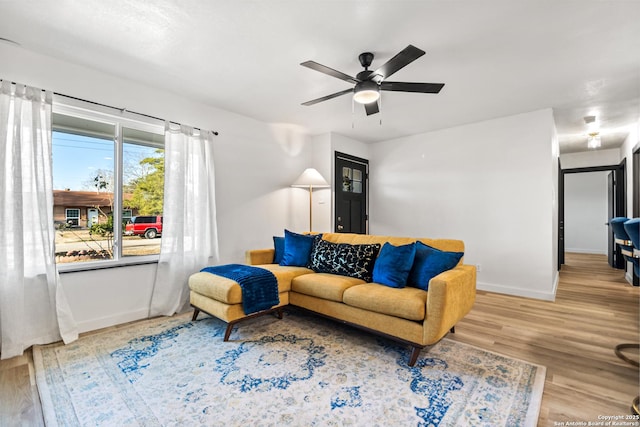 living room featuring a ceiling fan, baseboards, and wood finished floors