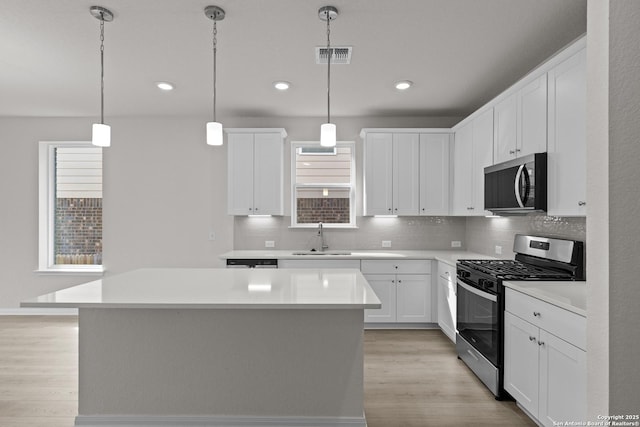 kitchen with stainless steel appliances, light countertops, and white cabinets