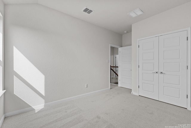 unfurnished bedroom with light colored carpet, a closet, visible vents, and baseboards