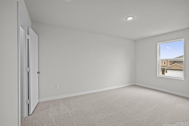 empty room featuring light carpet, baseboards, and recessed lighting