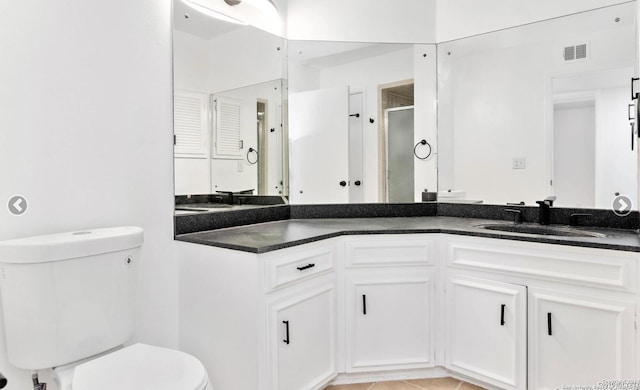 bathroom featuring visible vents, a stall shower, vanity, and toilet