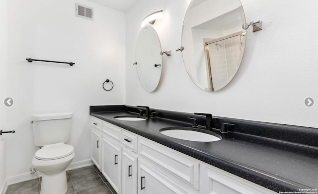 bathroom with toilet, double vanity, visible vents, and a sink