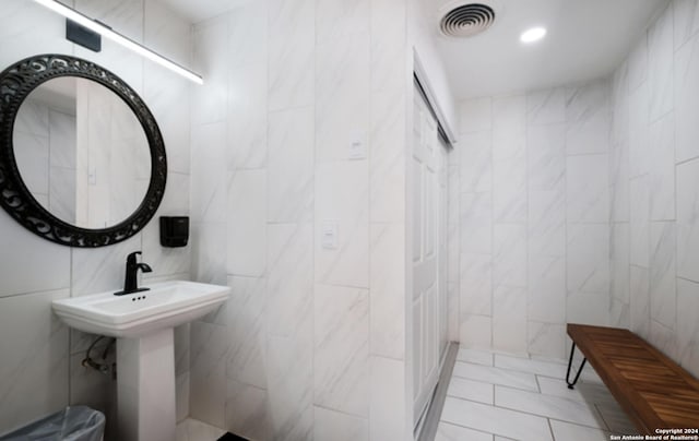 bathroom with a sink, visible vents, tile walls, and recessed lighting