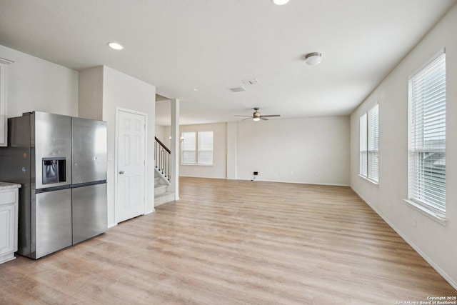 kitchen with light countertops, light wood-style floors, open floor plan, ceiling fan, and stainless steel fridge