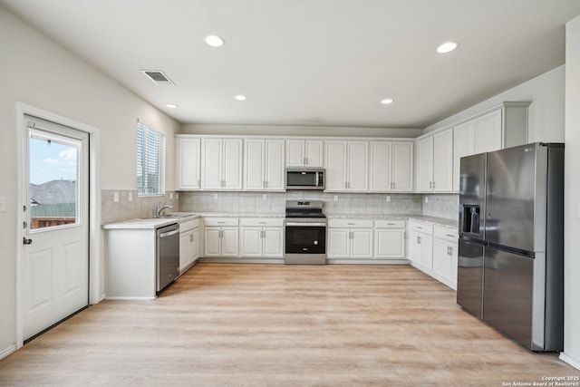 kitchen featuring light countertops, visible vents, light wood-style flooring, appliances with stainless steel finishes, and white cabinetry